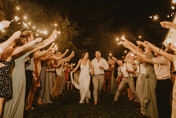 Couple celebrating their wedding surrounded by guests holding sparklers, creating a festive atmosphere.