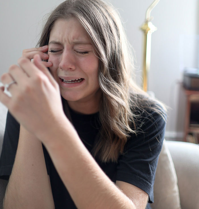 Crying woman on the phone, distressed after dog's disappearance during trip.