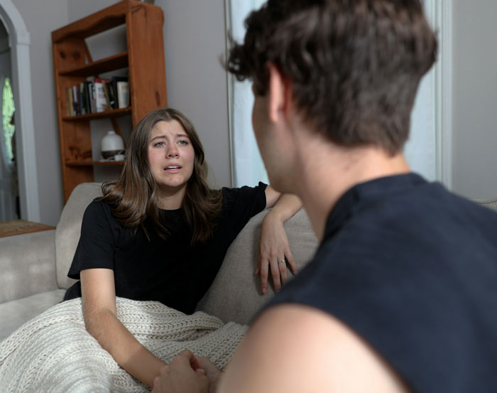 Woman upset on couch talking to man about lost dog experience.