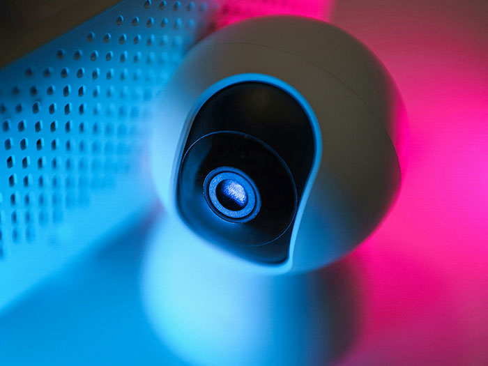 A security camera with blue and pink lighting, used for capturing evidence.