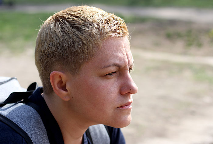 A person with short hair looking thoughtful outdoors, capturing assumptions about appearance and identity.