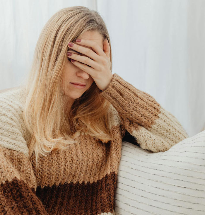 Woman sitting with hand on her face, appearing frustrated; topic relates to refusing to babysit for parents.