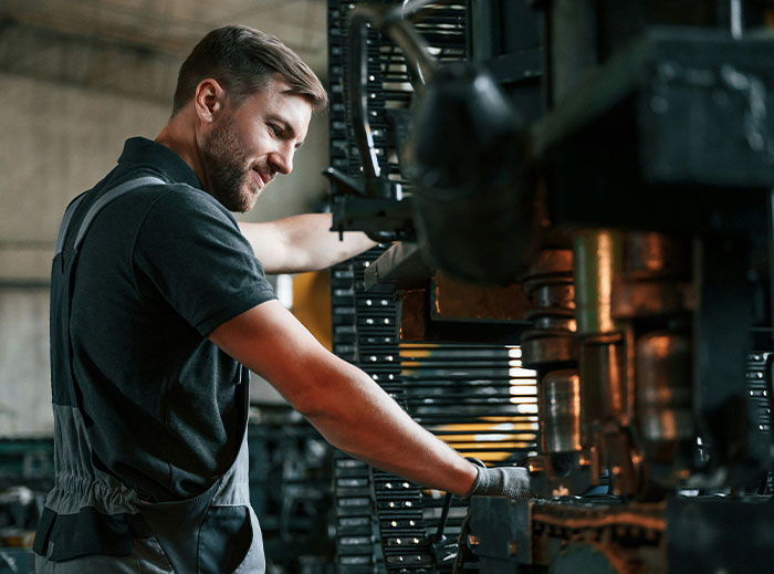 Employee working at a machine with a focused expression, demonstrating workplace skills.