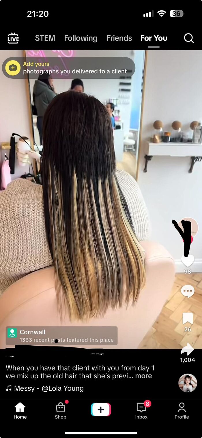 Woman with unevenly dyed hair showing a hair fail in a salon mirror.