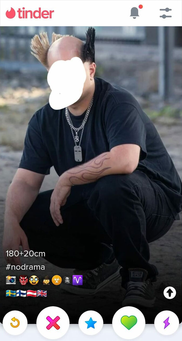 Man with a unique hairstyle squatting outdoors, showcasing a hair fail with spiky tufts on the sides.