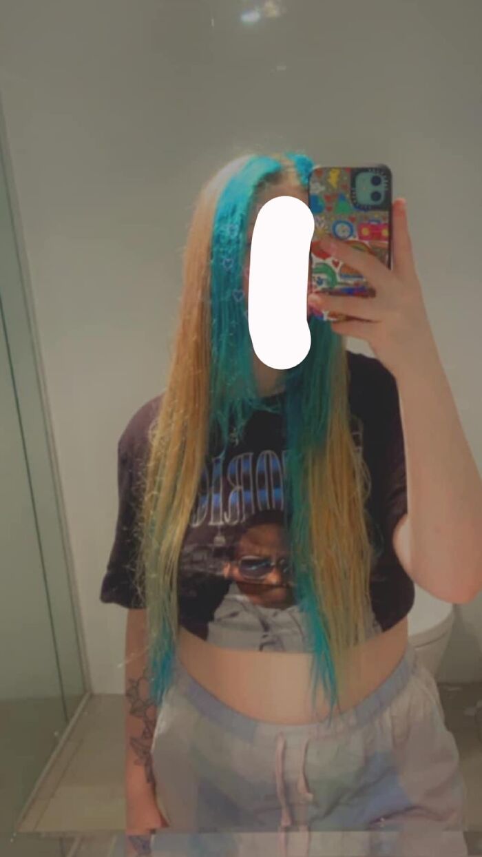 Person with a blue and blonde hair fail taking a mirror selfie in a bathroom.