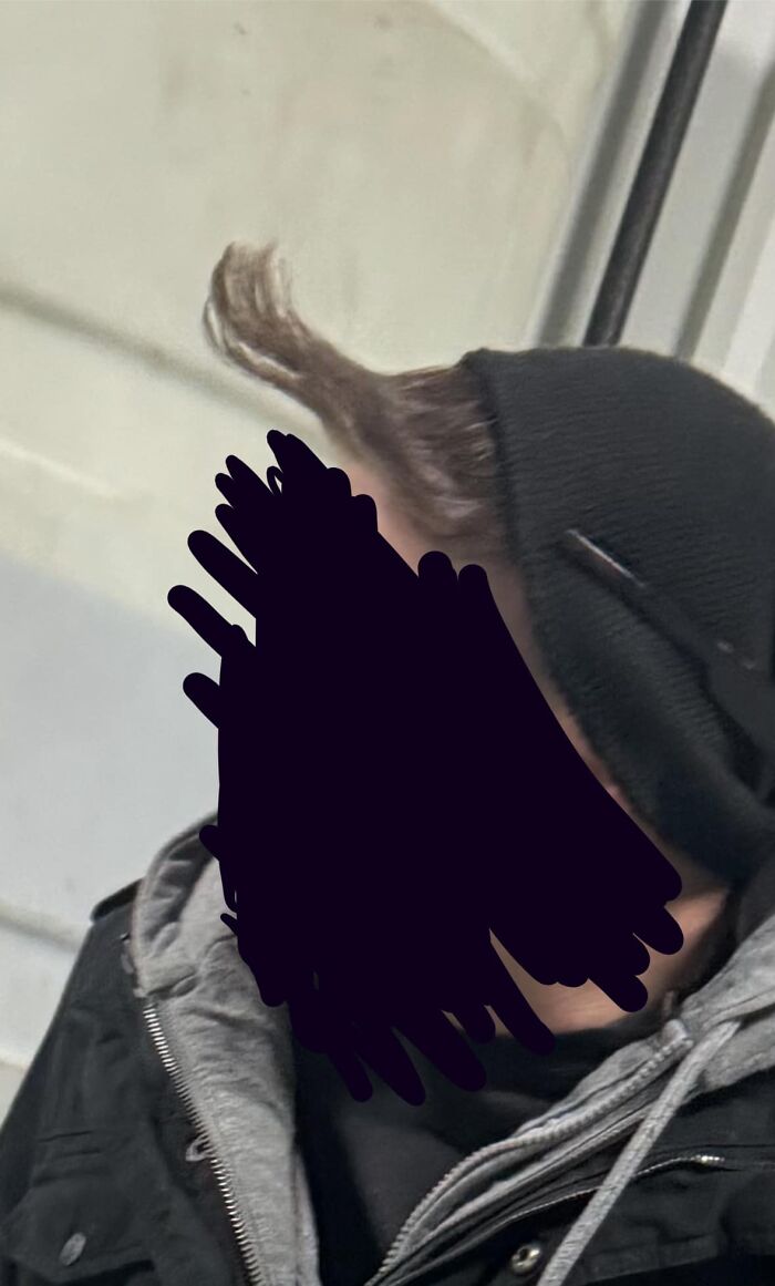 A person with an unusual hairstyle fail, wearing a black beanie and coat.