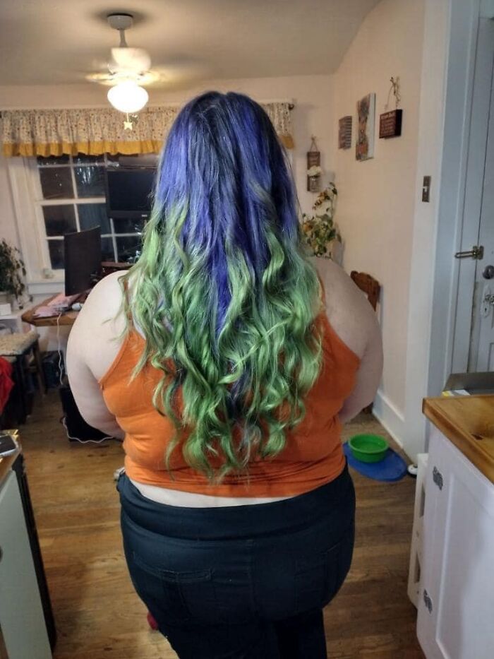 Colorful hair fail with uneven purple and green dye in home setting.