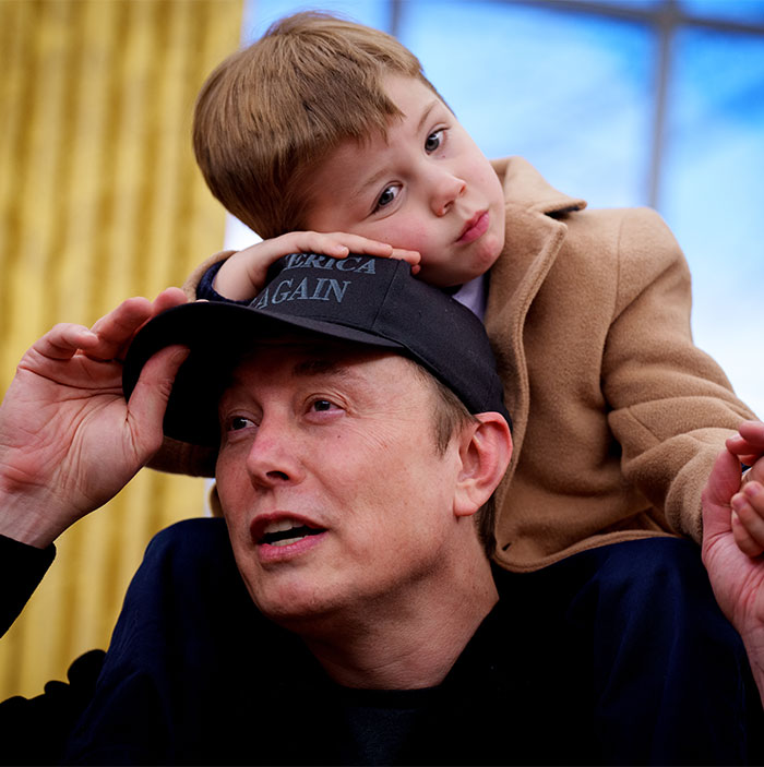 Man in a cap carrying a child on his shoulders, gazing ahead.