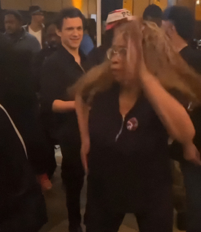 Tom Holland smiling at a lively family party, surrounded by guests.