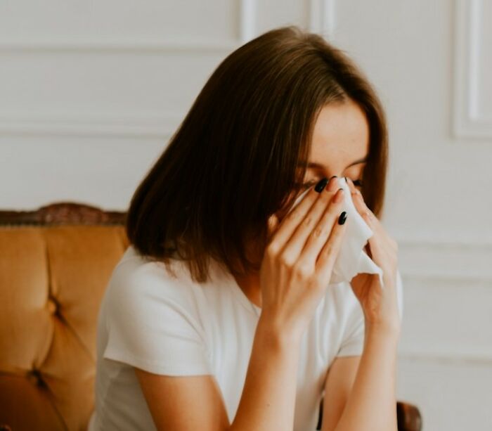 A woman in a white shirt, appearing emotional, holds a tissue, possibly reacting to a wedding objection story.