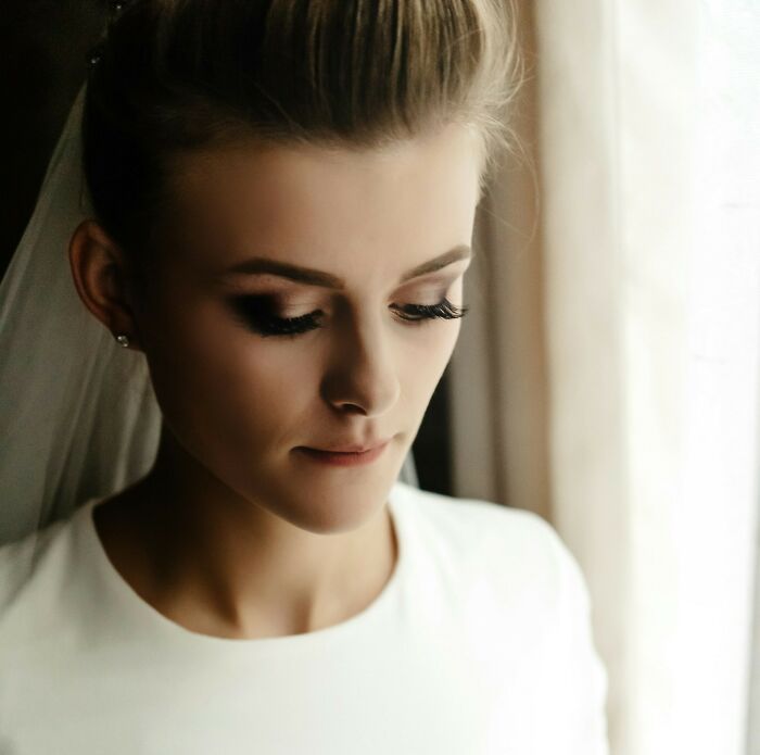 Bride in a serene moment by a window before the wedding ceremony.