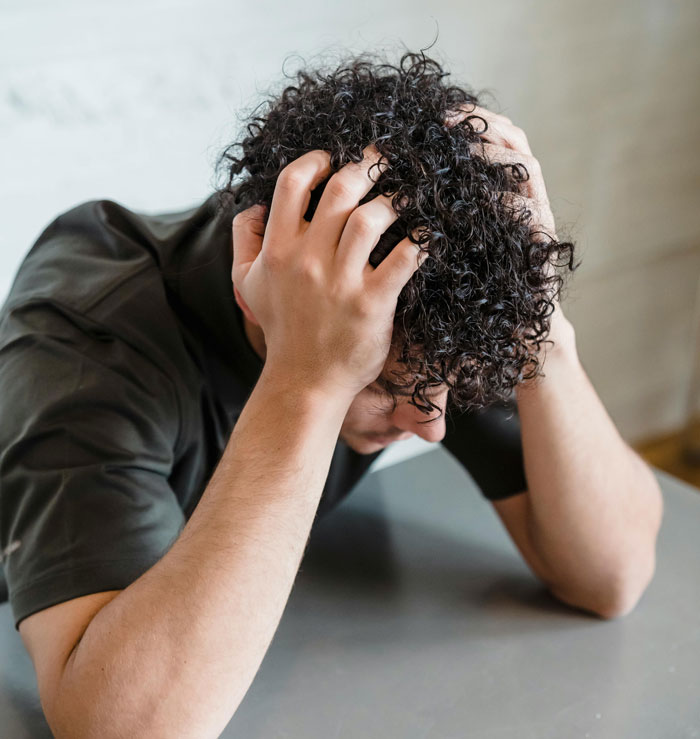 Stressed man with hands on head, feeling pressured about taking on a parental role.