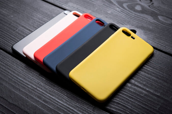 Colorful cheap phone cases on a wooden surface, showcasing inexpensive alternatives.