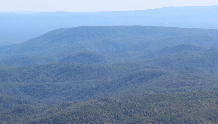 Expansive view of rolling green hills and valleys, showcasing cool natural landscapes under a clear sky.