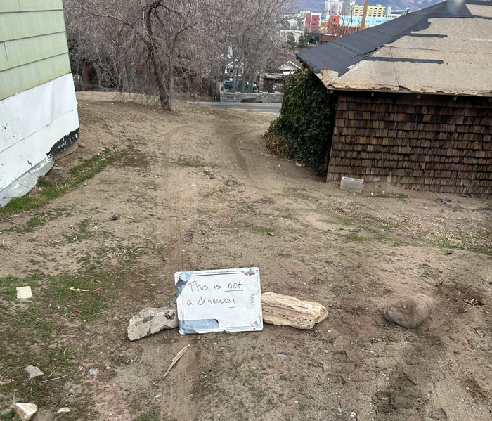 Sign reads "This is not a driveway" on yard to prevent neighbors from driving, DIY deterrent solution visible.