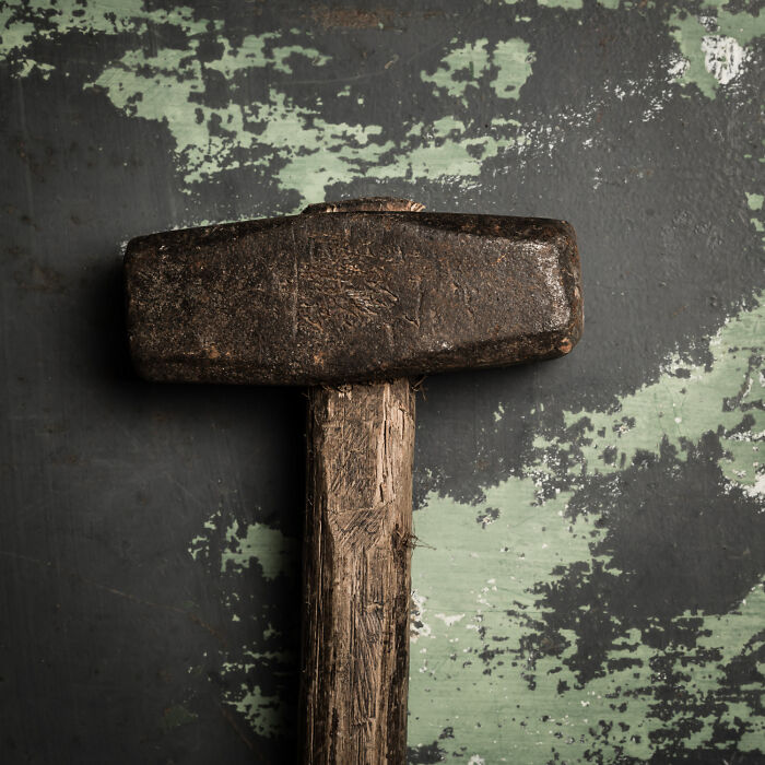 A rustic hammer with a weathered handle on a distressed background, illustrating a cheap version of a useful tool.