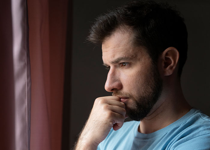 Father looks frustrated while thinking, related to daughter’s name pronunciation issue with teacher.