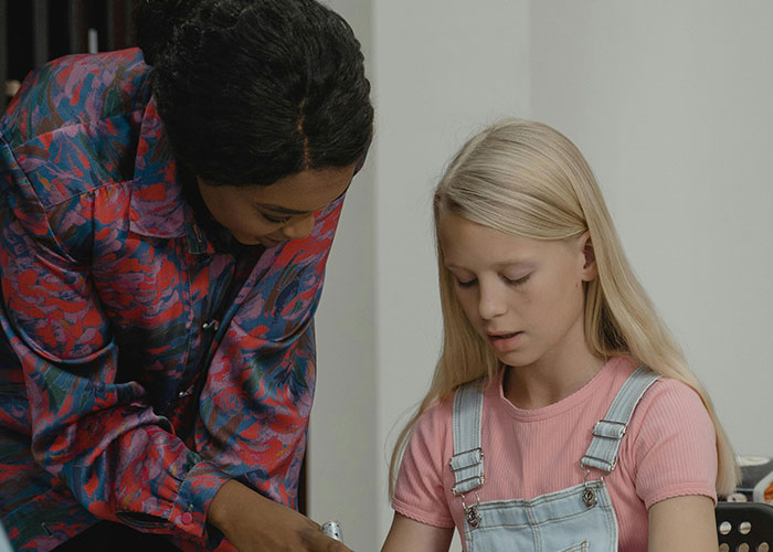 Teacher assisting a student in a classroom setting, focused on proper name pronunciation.