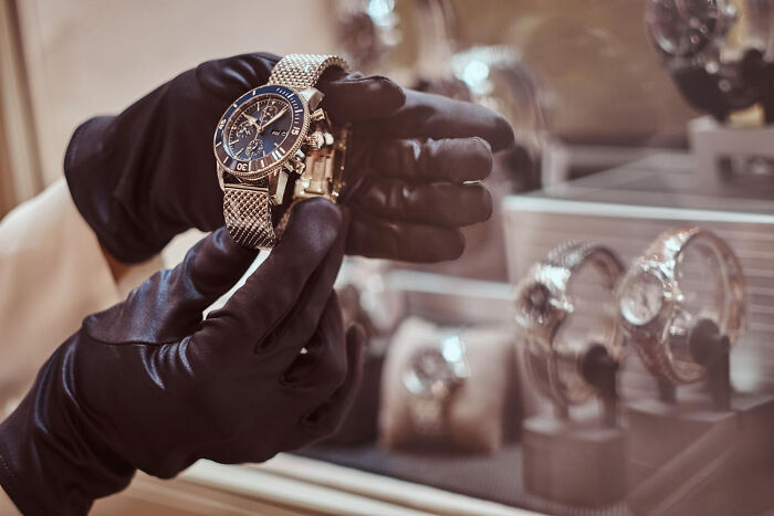 Affordable luxury watch being held by gloved hands in a shop display.