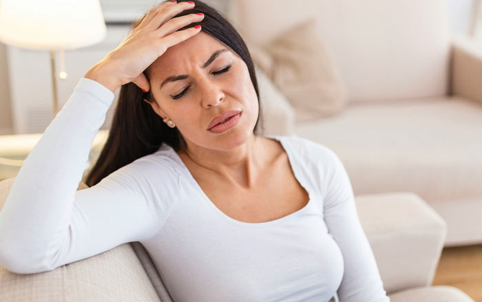 Woman in white shirt looking stressed, representing family tension over massive fortune inheritance.