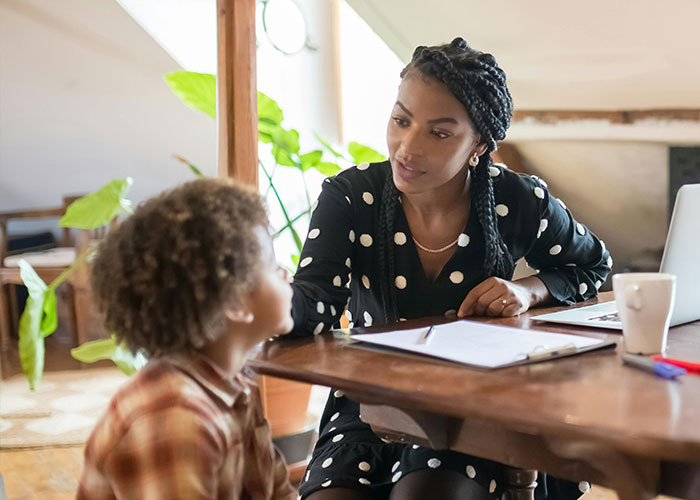 Mom uses gentle parenting technique in conversation with child at a wooden table, emphasizing empathy and understanding.