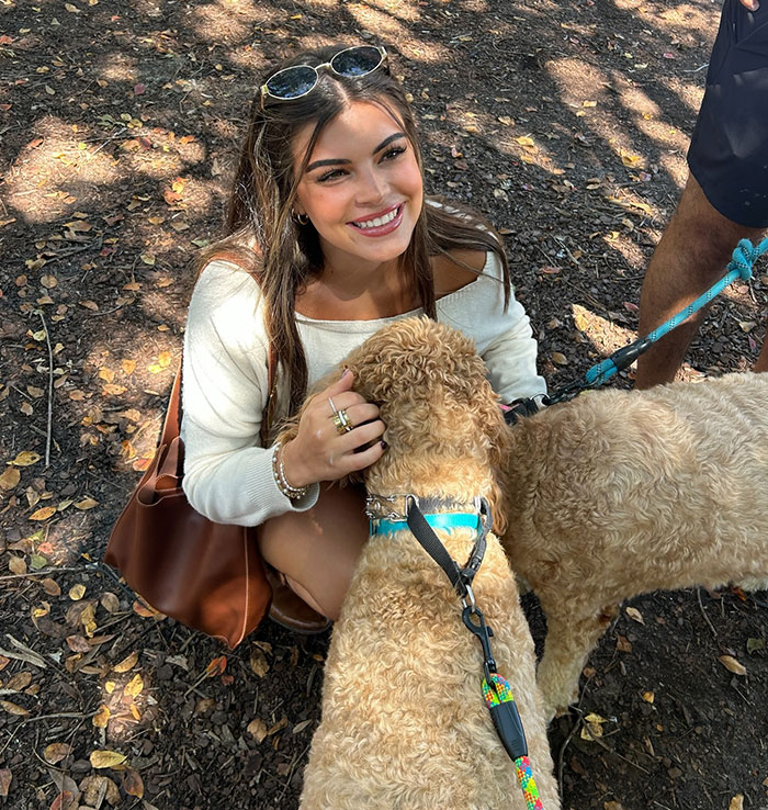 Smiling woman outdoors with two dogs.