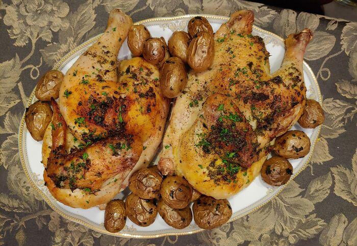 Roasted chicken with herbs and potatoes on a decorative plate, perfect for indulging when seeking cool Wikipedia articles.