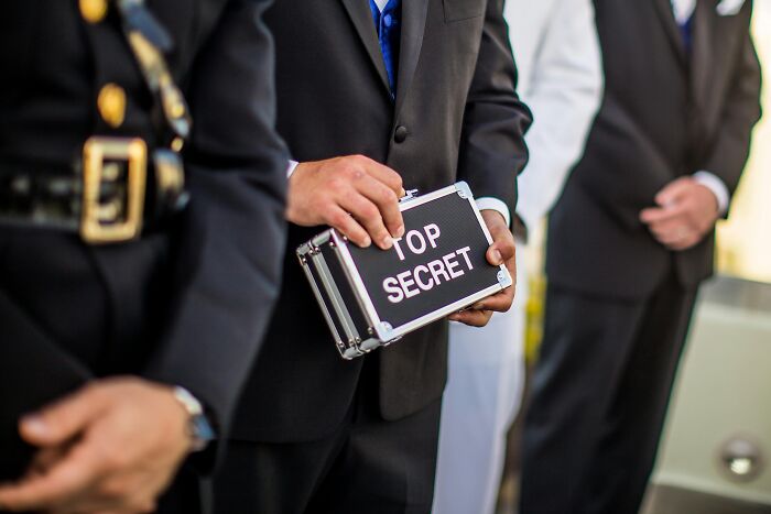 Person holding a &ldquo;Top Secret&rdquo; briefcase while standing in a line, symbolizing intrigue often found in Wikipedia articles.