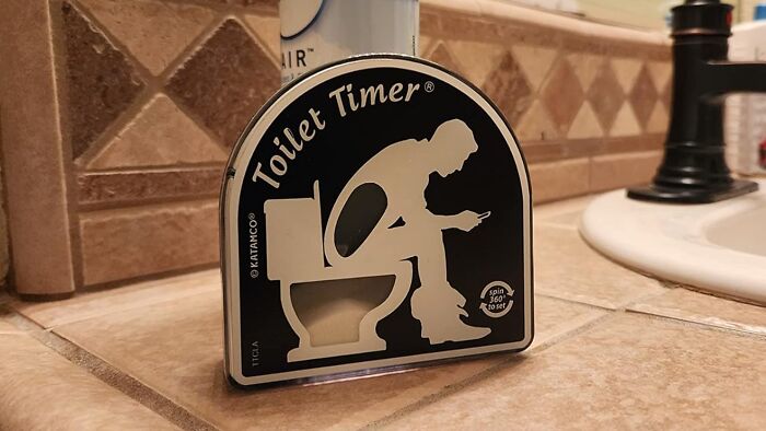 Toilet humour-themed timer on a bathroom counter, featuring a silhouette of a person sitting on a toilet using a phone.