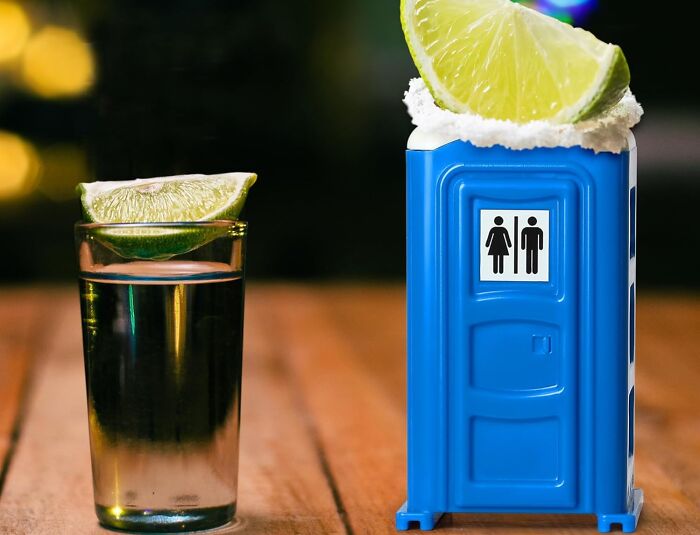 Tequila shot with lime next to a portable toilet-shaped glass, highlighting toilet humour.