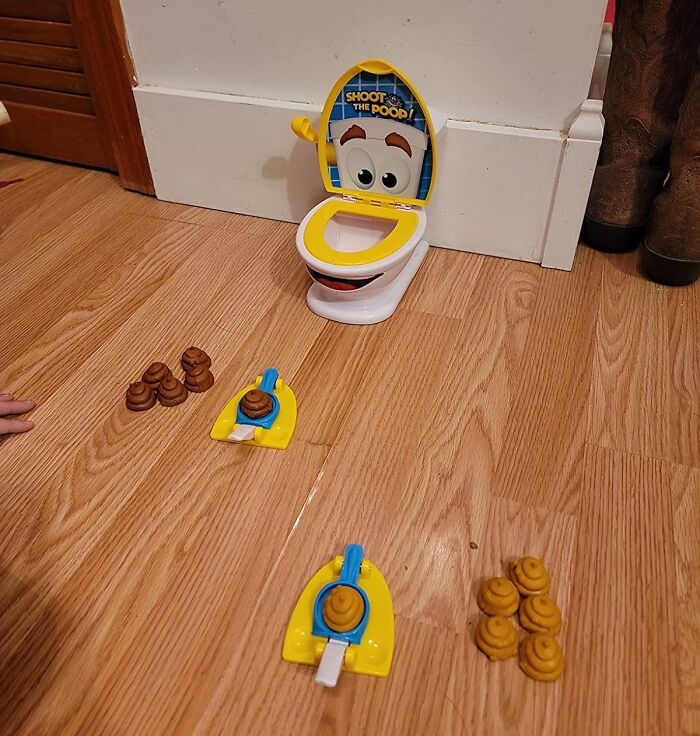 Toy toilet game on wooden floor with poop-shaped pieces, highlighting toilet humour theme.