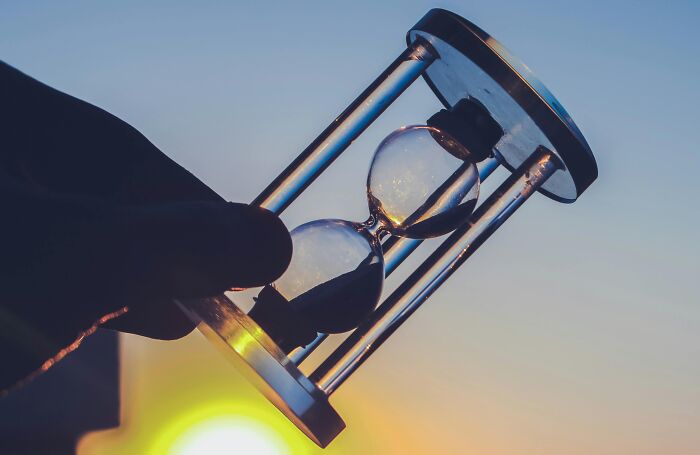 Hand holding hourglass against sunset, symbolizing time spent reading Wikipedia articles.