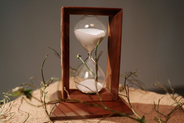 Hourglass on sand surrounded by twigs, symbolizing the passage of time and lost hours reading cool Wikipedia articles.