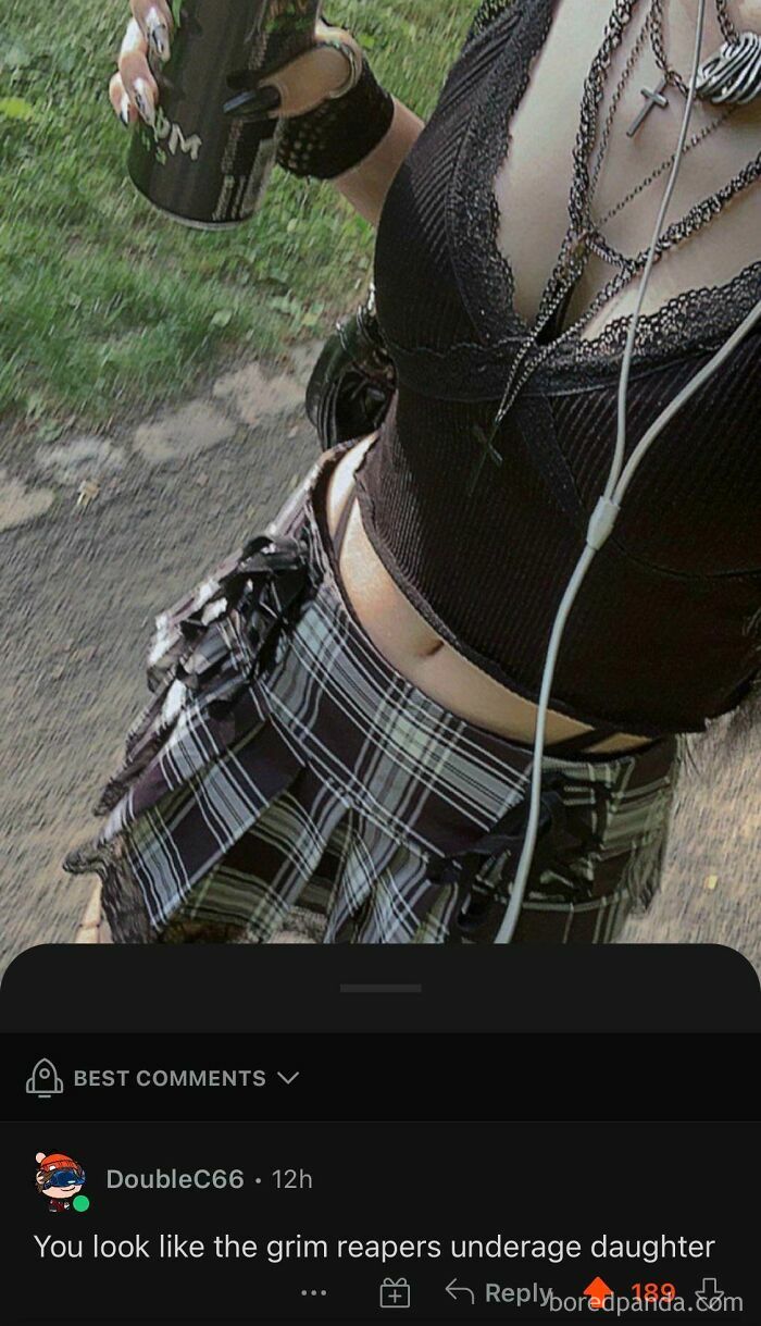 Person in goth attire holding a drink, receiving rare compliments online, with a plaid skirt and layered necklaces.