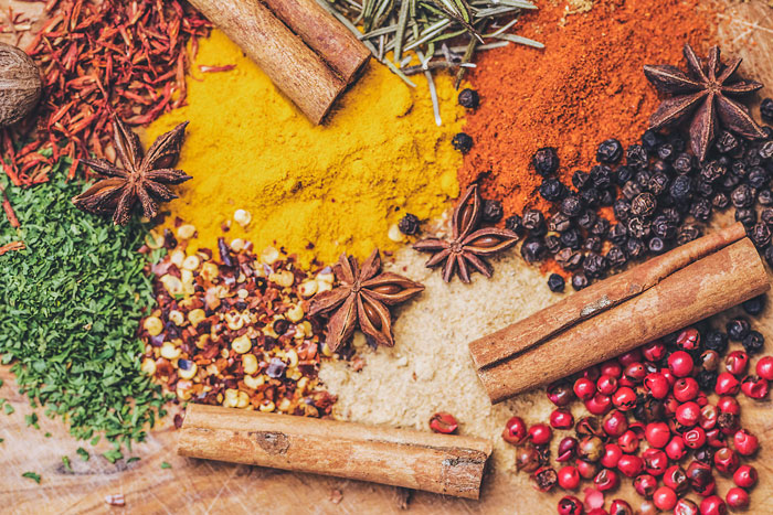 Various spices on a wooden surface, including cinnamon sticks and star anise, used in diverse cooking.