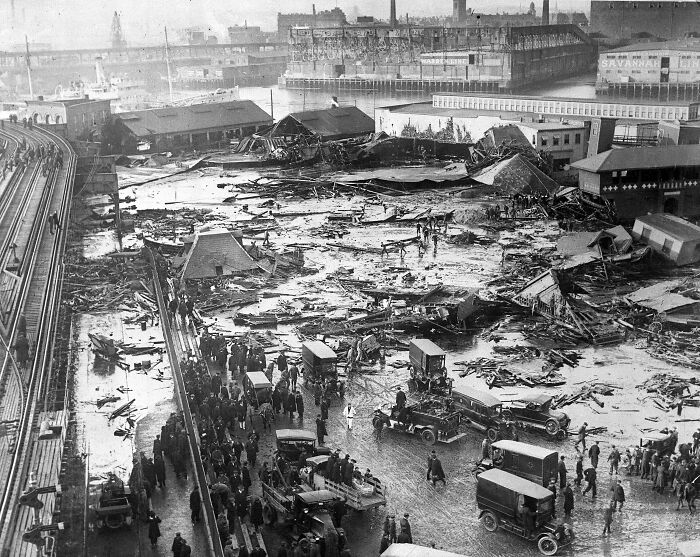 Historic flood aftermath with debris and vintage cars at a waterfront, illustrating cool Wikipedia article topics.