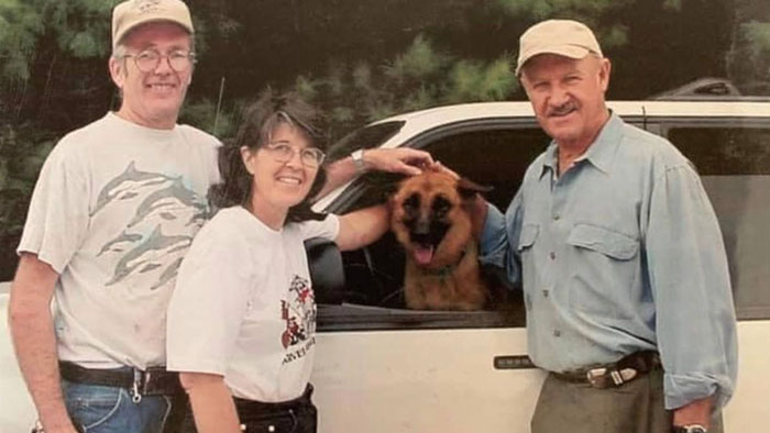 Three people smiling with a dog in a car window, related to Gene Hackman's investigators discussing the passing of dog Zinna.