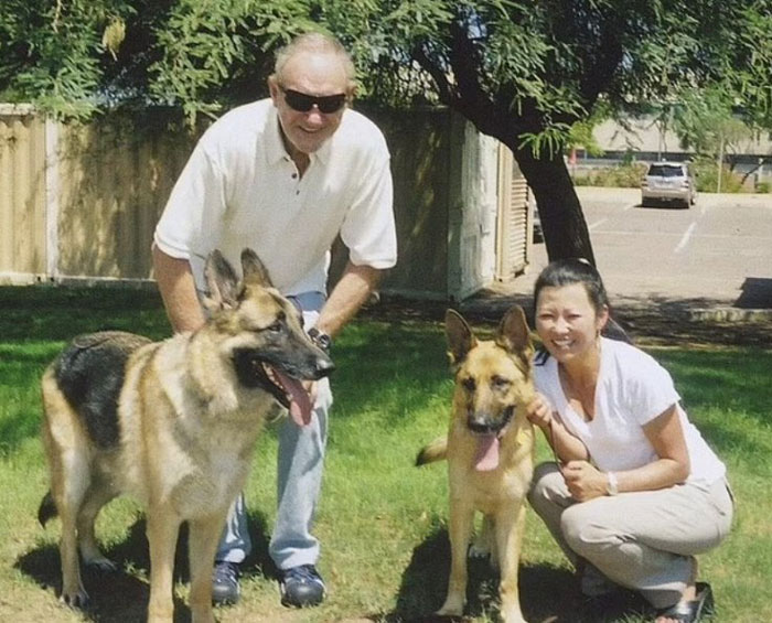 A person and a woman with two dogs on grass, focusing on the topic of Gene Hackman's dog Zinna.