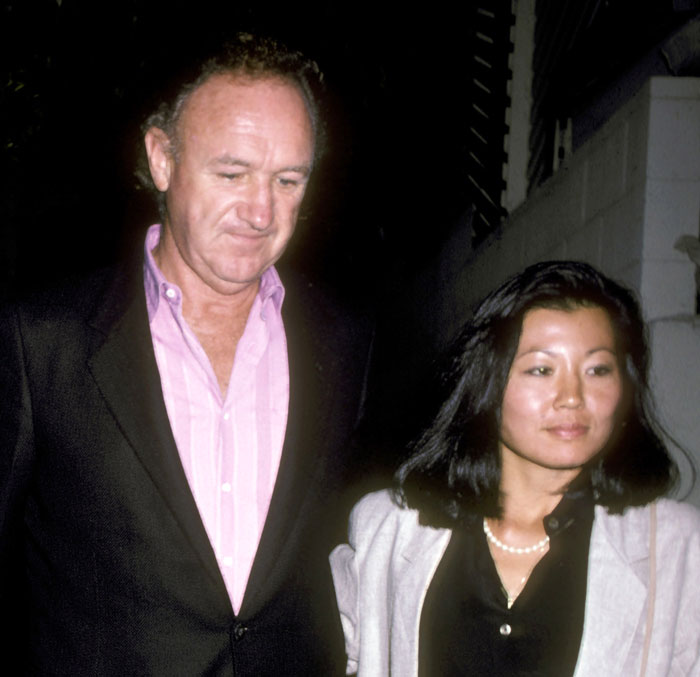 A man and a woman walking together at night in formal attire.