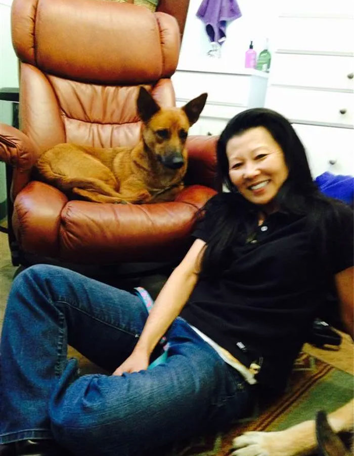 Woman smiling with a dog sitting on a brown leather chair, related to Gene Hackman’s investigators.