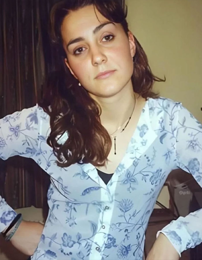 Young woman in a floral blouse, before becoming a princess, stands confidently with hands on hips.