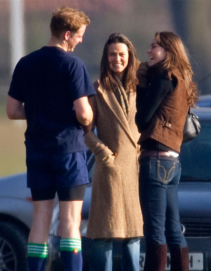 Three people chatting outdoors on a sunny day, two women in casual wear, one man in sports attire, smiling and relaxed.