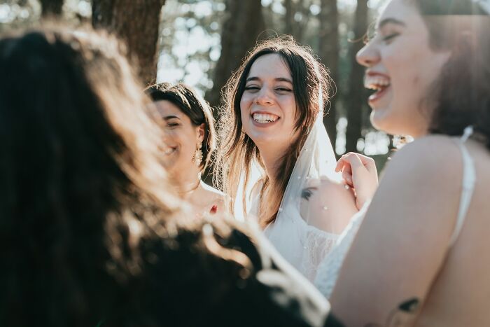 Women smiling in a wedding setting, capturing joyful moments despite objections from guests.