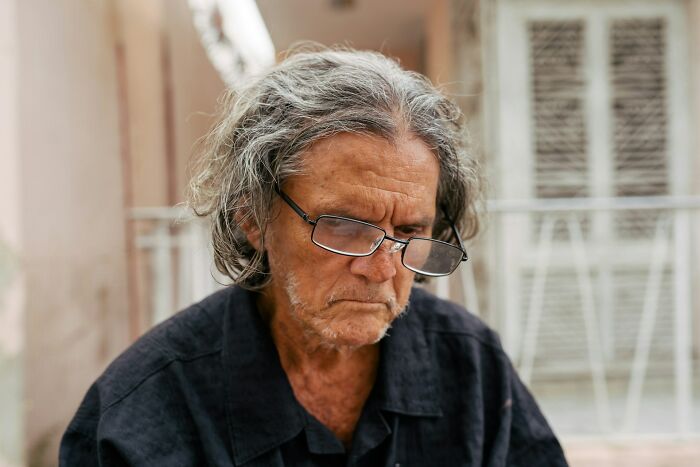 Elderly man wearing glasses, looking thoughtful, possibly reflecting on a wedding objection story.