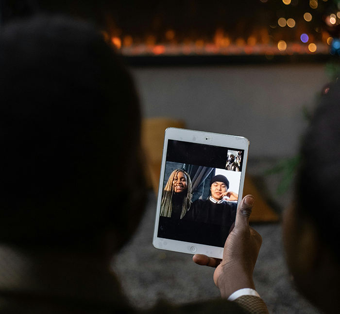 Person using a tablet for a video call with childfree friends during holiday season.