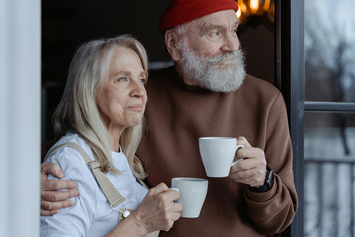 Elderly couple enjoying coffee by a window, showing a warm and cozy moment.