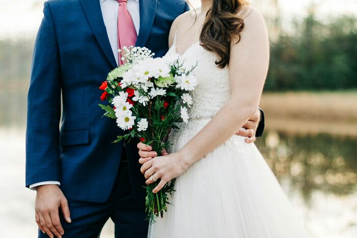 Bride and groom standing together outdoors, the bride holding a bouquet, capturing the essence of wedding stories and guest objections.