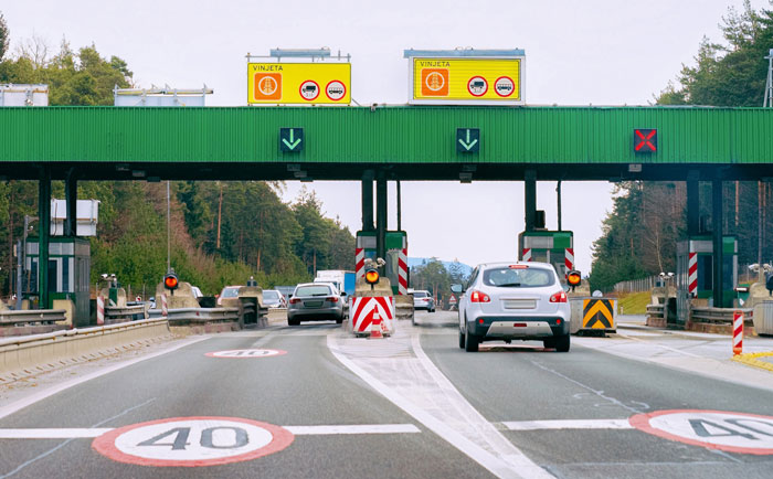 Cars at a toll booth on a highway, symbolizing driver-paid tolls and petty revenge.