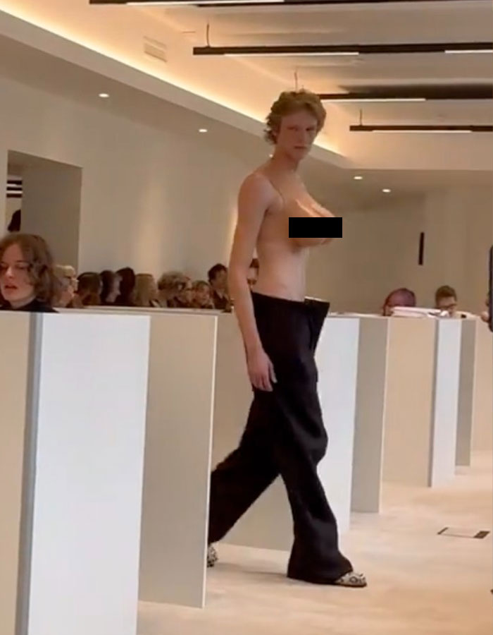 Model wearing a bold male top imitating a female chest at Paris Fashion Week runway show.